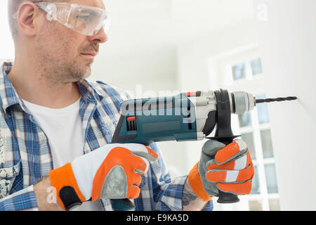 Mid-Adult Mann Bohrloch in Wand Stockfoto