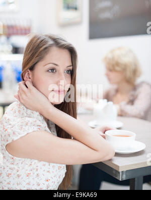 Nachdenkliche junge Frau mit Kaffee im café Stockfoto