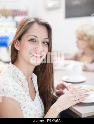 Porträt der schönen jungen Frau mit Kaffee am Tisch im café