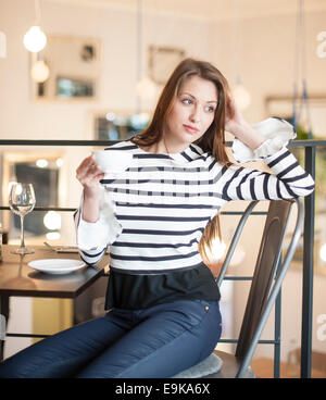Nachdenkliche junge Frau wegsehen bei Kaffee im café Stockfoto