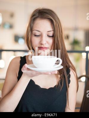 Schöne junge Frau mit Kaffee-Tasse und Untertasse im café Stockfoto