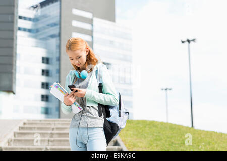 Junge Frau mit Smartphone am College campus