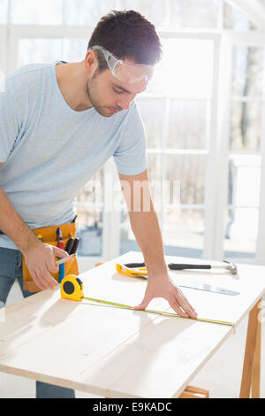 Mid-Adult Mann Kennzeichnung Tisch mit Maßband Stockfoto