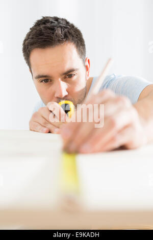 Mid-Adult Mann Kennzeichnung Tisch mit Maßband Stockfoto