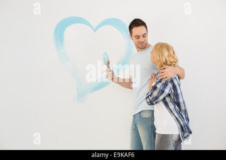 Liebespaar im mittleren Erwachsenenalter mit gemalten Herzen an Wand Stockfoto