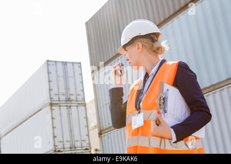 Ingenieurin mit Walkie-talkie im Frachthafen Stockfoto