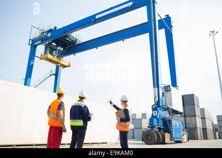 Arbeiter gegen Großkran laden Container am Frachthafen diskutieren Stockfoto