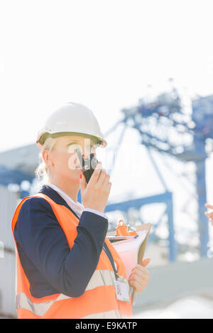 Ingenieurin mit Walkie-talkie im Frachthafen Stockfoto