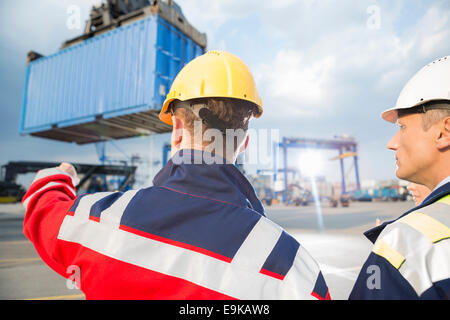 Rückansicht der männlichen Arbeitnehmer im Frachthafen diskutieren Stockfoto