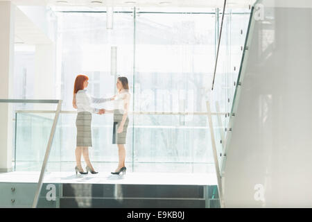 Full-length Geschäftsfrauen Händeschütteln im Büro Stockfoto