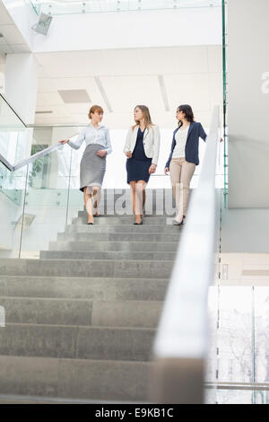 Unternehmerinnen im Gespräch während der Bewegung nach unten Schritte im Büro Stockfoto