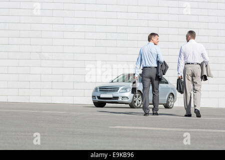 Rückansicht des Geschäftsleute tragen Aktentaschen während des Gehens auf Auto auf der Straße Stockfoto