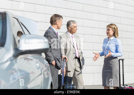 Geschäftsleute mit Gepäck außerhalb Auto diskutieren Stockfoto