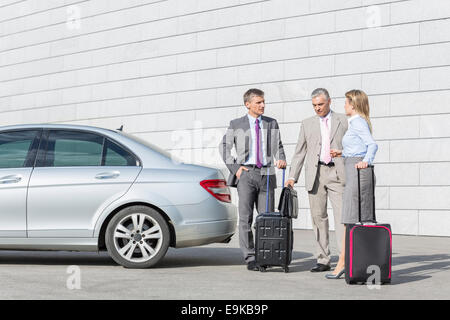 Geschäftsleute mit Gepäck auf Straße außen Auto diskutieren Stockfoto