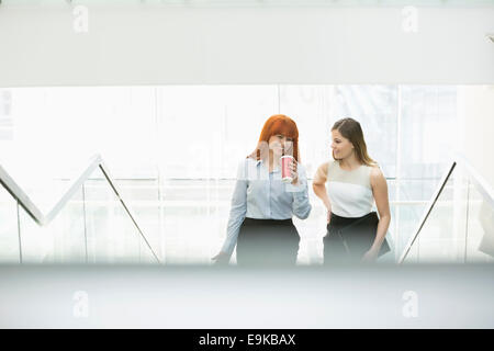 Geschäftsfrauen Kaffeetrinken während der Bewegung Stufen im Büro Stockfoto