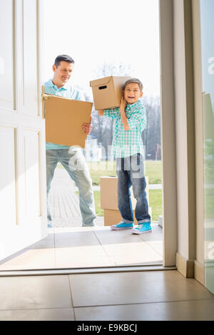 Glücklicher Vater und Sohn mit Kartons in neues Haus betreten Stockfoto