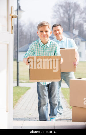 Glücklicher Vater und Sohn mit Kartons in neues Zuhause Stockfoto