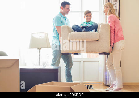 Eltern mit Sohn auf Sessel im neuen Haus Stockfoto