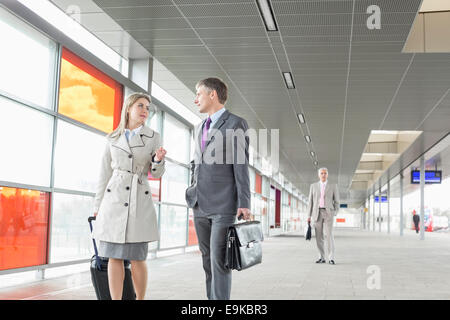 Unternehmer und Unternehmerin im Gespräch während des Gehens im Bahnhof Stockfoto