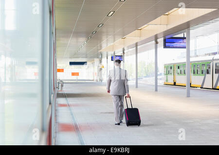 Voller Länge Rückansicht der Geschäftsmann mit Gepäck zu Fuß in Eisenbahn-Plattform Stockfoto