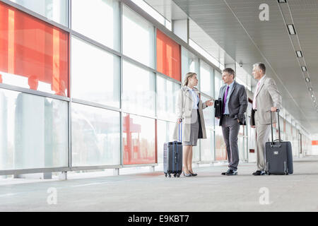 Voller Länge von Geschäftsleuten mit Gepäck am Eisenbahn-Plattform sprechen Stockfoto