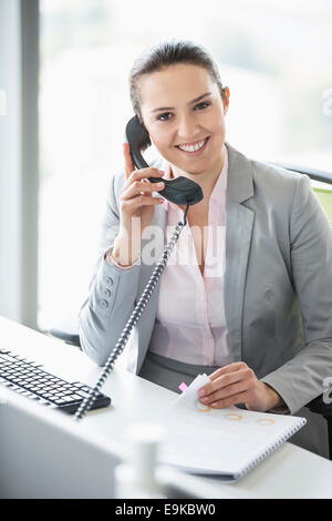 Lächelnde junge Geschäftsfrau Gespräch am Telefon im Büro Stockfoto