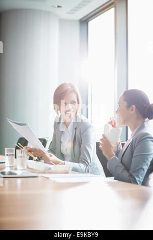 Junge Unternehmerinnen während dem Mittagessen am Tisch im Büro arbeiten Stockfoto