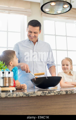 Glücklicher Mann mit Kindern, die Zubereitung von Speisen in der Küche Stockfoto