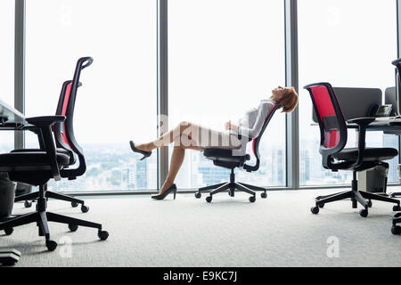Voller Länge Seitenansicht der junge Geschäftsfrau lehnt sich zurück auf den Stuhl im Büro Stockfoto