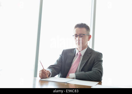 Reife Geschäftsmann auf Buch am Tisch im Büro schreiben Stockfoto
