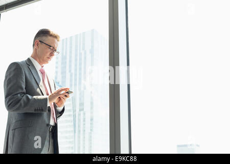 Reife Geschäftsmann mit Handy-Fenster Stockfoto