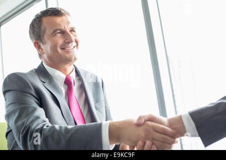 Lächelnd reifer Geschäftsmann Händeschütteln mit Partner im Büro Stockfoto