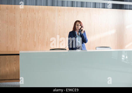 Angestellte an der Rezeption sprechen am Telefon im Büro Stockfoto