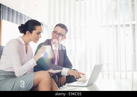 Unternehmer und Unternehmerin diskutieren über Laptop im Büro Stockfoto