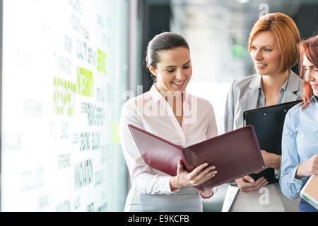 Unternehmerinnen mit Datei-Ordner im Büro Flur diskutieren Stockfoto