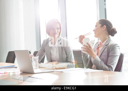 Junge Unternehmerinnen mit Mittagessen am Tisch im Büro Stockfoto