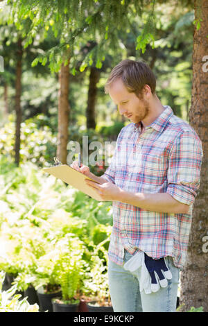 Männlichen Vorgesetzten schreiben auf Zwischenablage am Gärtnerei Stockfoto