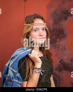 Junges schönes Mädchen gekleidet im Hippie-Stil, vor dem Hintergrund der Burgunder Metallwand. Stockfoto