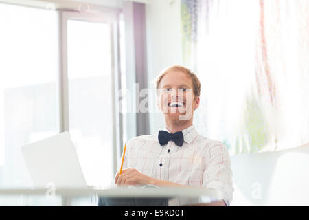 Fröhlich sitzen am Schreibtisch im Kreativbüro Geschäftsmann Stockfoto