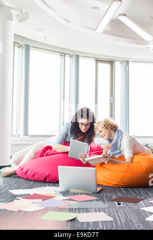 Unternehmerinnen mit tablet-PC beim Entspannen auf Sitzsäcke bei Kreativbüro Stockfoto