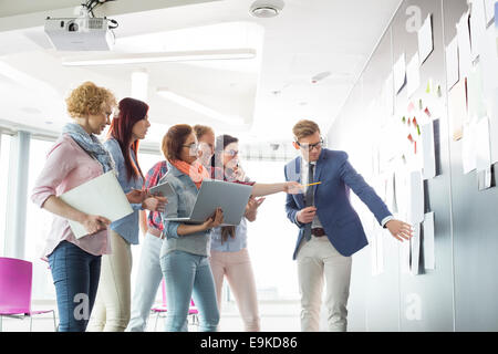 Kreative Unternehmer diskutieren über Dokumente an Wand im Büro Stockfoto