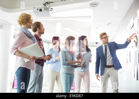 Unternehmer diskutieren über Dokumente an Wand in Kreativbüro Stockfoto