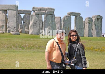 Ein lächelndes touristische Paar für ein Foto an einem warmen, sonnigen Tag in Stonehenge in Wiltshire, England, Großbritannien dar. Stockfoto
