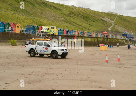 RNLI Patrouille am Strand von Whitby, N Yorks, UK. Im Hintergrund sieht man ein NHS Krankenwagen. Querformat; Textfreiraum. Stockfoto