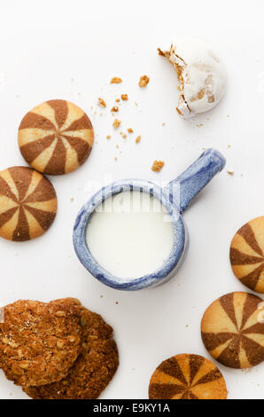 Glas Milch und verschiedene Cookies auf weißem Hintergrund Stockfoto