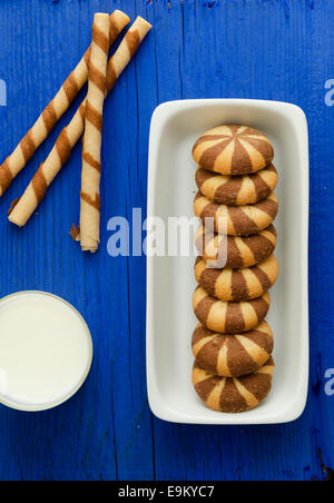 Gestreifter Schoko Waffelröllchen und Pfahl Kekse auf blauem Hintergrund Stockfoto
