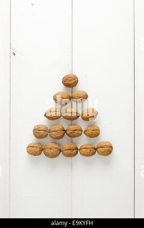 Walnüsse in einer Pyramidenform angeordnet über weißen Holztisch Stockfoto