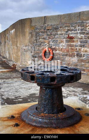 Rostige alte Harbourside Capstan an Cullen mit der Haupthafen Wand im Hintergrund Stockfoto