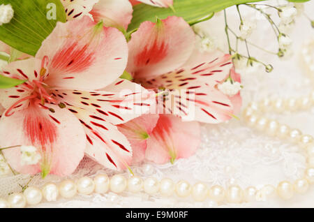 Bouquet von rosa Blüten und Perlen auf weißer bestickter Spitze Stockfoto