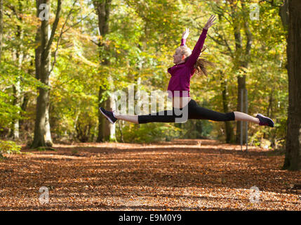 junge Frau tut Split Sprung Sprung in der herbstlichen Wälder Stockfoto